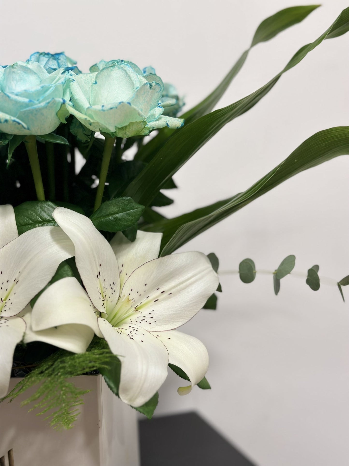 Blue Roses and White Lilies in a White Box.